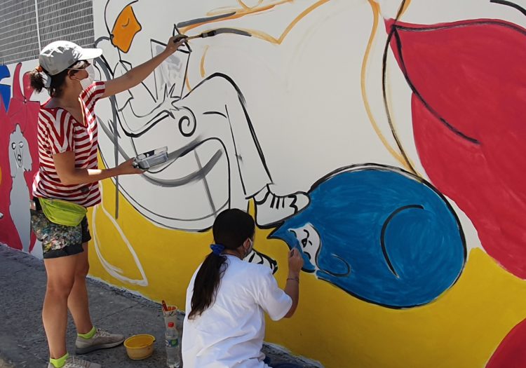 Foto de dos personas pintando un mural