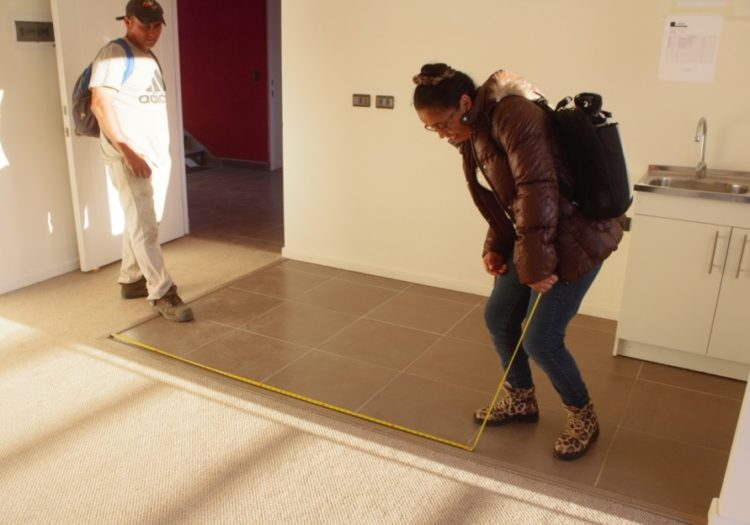 foto de dos personas midiendo el piso con una huincha de medir